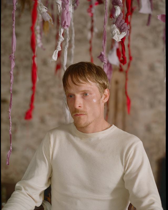 Shawn sits beneath red and white ribbons, watchful.