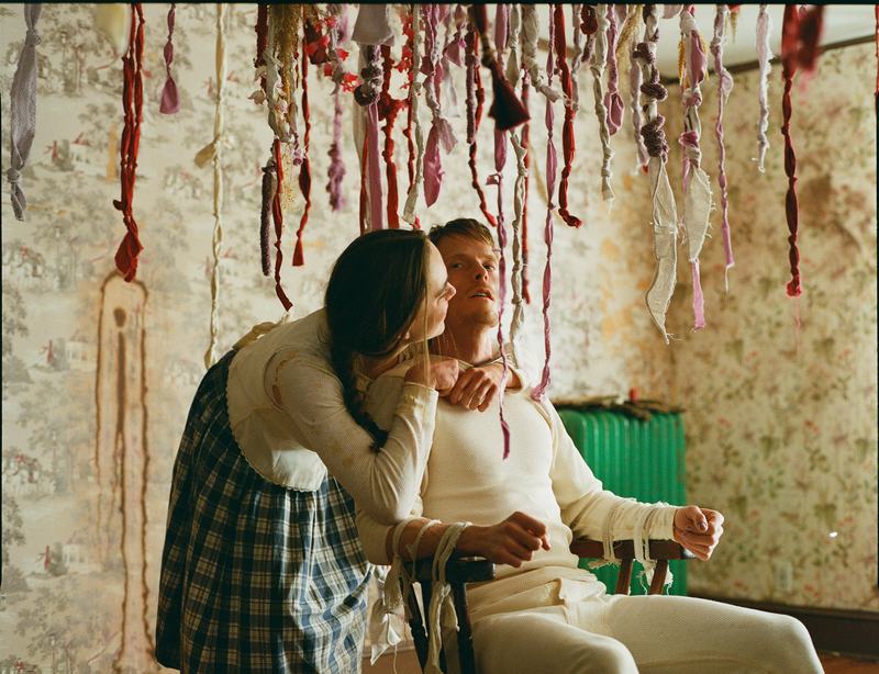 A sister leans over Shawn, seated in a chair beneath the ribbons.