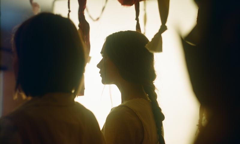 Two silhouettes against a bright window.